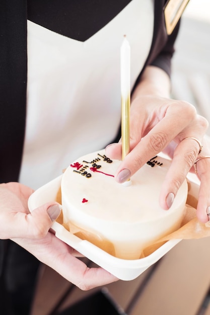 Bento-Kuchen mit einer Kerze mit der Hand eines Mädchens. Nahaufnahme Kleine Überraschung zum Geburtstag eines Mädchens
