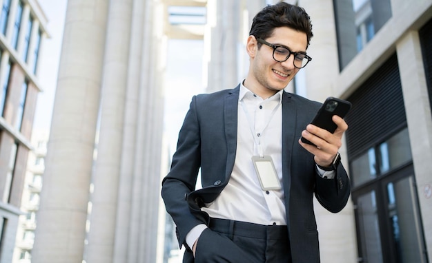 Benutzt das Telefon, schreibt dem Kunden eine Nachricht, ein Mann mit Brille und formellem Anzug, ein Geschäftsmann