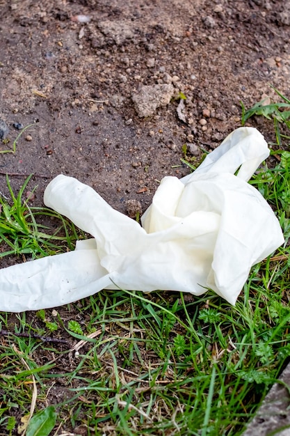 Benutzter weißer medizinischer Handschuh auf dem Gras