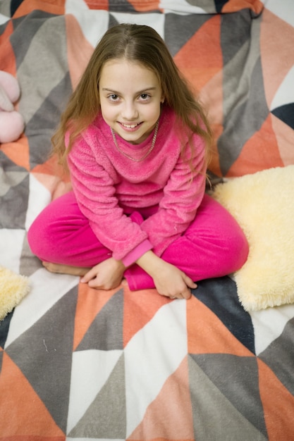 Bequemer Pyjama zum Entspannen Mädchen kleines Kind trägt einen weichen, süßen Pyjama, während er sich auf dem Bett entspannt