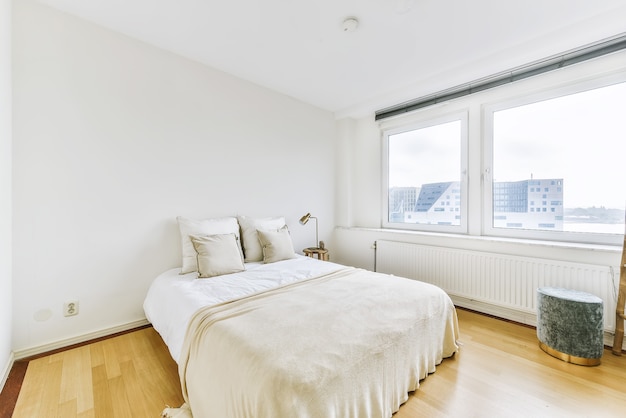 Bequemes Bett mit Decke und Kissen im geräumigen Schlafzimmer in moderner Wohnung