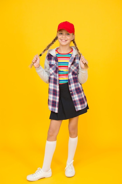 Bequemes Outfit. Modernes Outfit. Rebellischer Teenager. Streetstyle. Cooles Schulmädchen. Viel Spaß beim charismatischen Mädchen auf gelbem Hintergrund. Tomboy-Konzept. Teenageralter. Mädchen entzückender stilvoller Outfitjugendlicher.