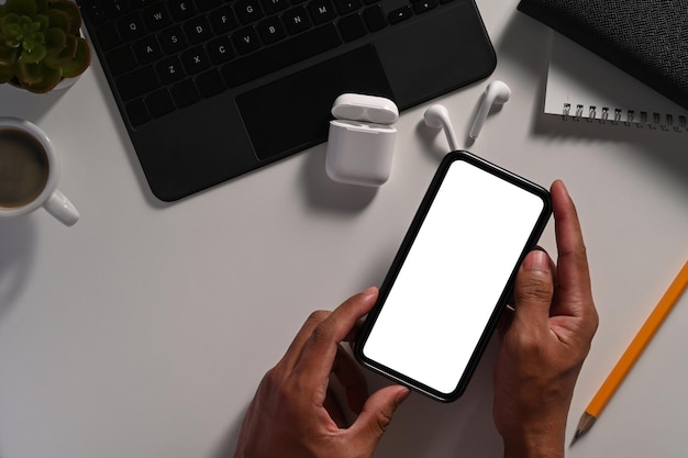 Über Ansicht Geschäftsmann Hand hält Smartphone mit leerem Bildschirm am Schreibtisch