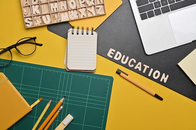 Über Ansicht Laptop-Brille und Schreibwaren auf gelbem Hintergrund Zurück zum Schulkonzept