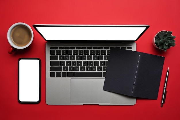 Über Ansicht Laptop-Computer, Smartphone, Kaffeetasse und Notebook auf rotem Grund.