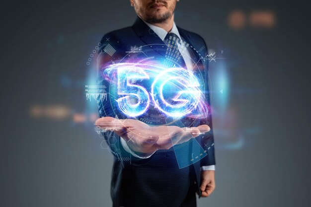 Über Hand des Geschäftsmannes 5G-Hologramm, kreativer Hintergrund. 5G-Netzwerkkonzept, mobiles Hochgeschwindigkeitsinternet, Netzwerke der neuen Generation. Gemischte Medien.