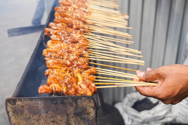 Über traditionellem Holzkohlefeuer gegrillter Hähnchen-Satay. Fleischspieße brennen mit Rauch