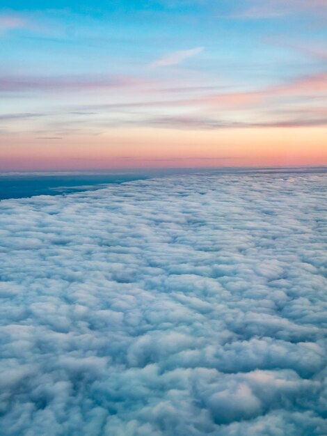 Über Wolken aus dem Flugzeugfenster bei natürlichem Dämmerungslicht