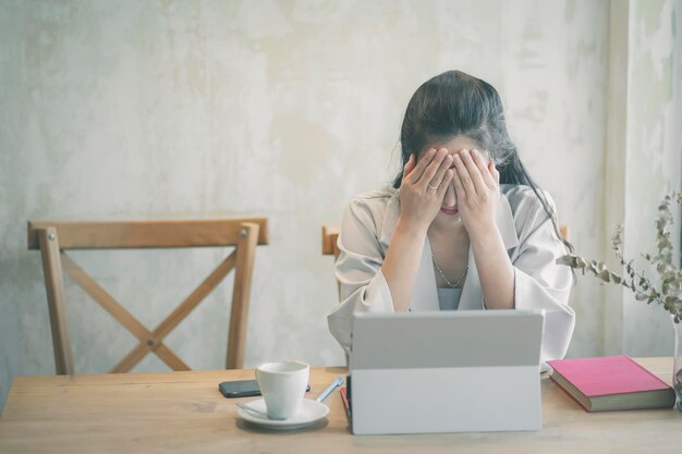 Überarbeitete Geschäftsfrau sitzt am Schreibtisch im Büro