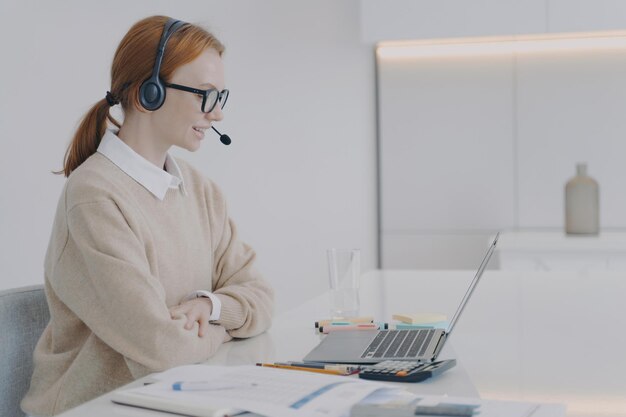 Beraterin im Headset arbeitet am Laptop im Büro Junge Frau ist Beraterin des Callcenters