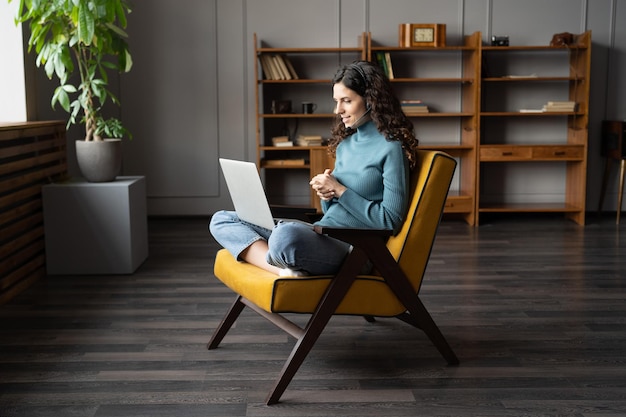 Beraterin in der Headset-Beratung per Laptop von zu Hause aus per Video-Chat mit dem Kunden