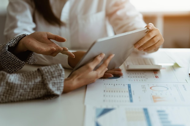 Beratung des Fondsmanagerteams und Diskussion über die Analyse des Aktienmarktes für Investitionen per digitalem Tablet auf dem Holzschreibtisch im Büro