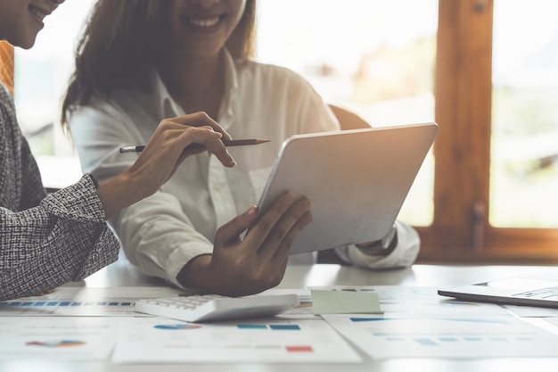 Beratung des Fondsmanagerteams und Diskussion über die Analyse des Aktienmarktes für Investitionen per digitalem Tablet auf dem Holzschreibtisch im Büro