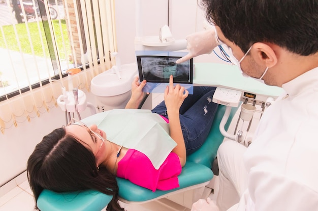 Überblick über ein junges Patientenschwester, die mit ihrem Zahnarzt im Büro ihre Zahnröntgenuntersuchung durchführt