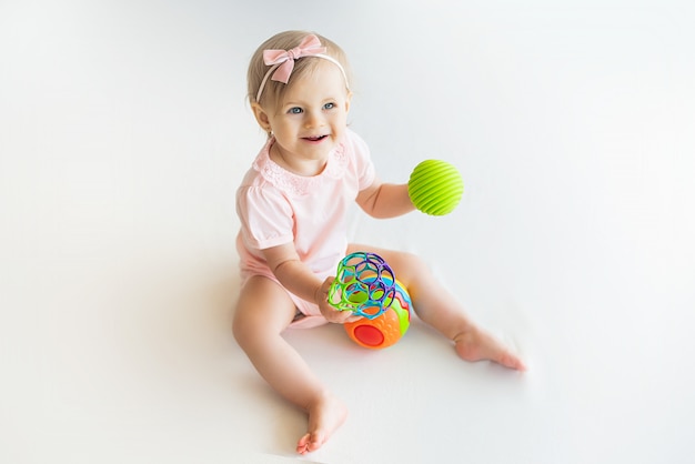 Berçário feliz menina brincando com bola de borracha colorida em casa
