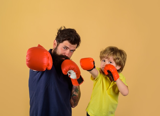 Bereit für den Sparring bärtiger Sportler, der Boxen kleiner Junge in roten Boxhandschuhen trainiert kleiner Junge