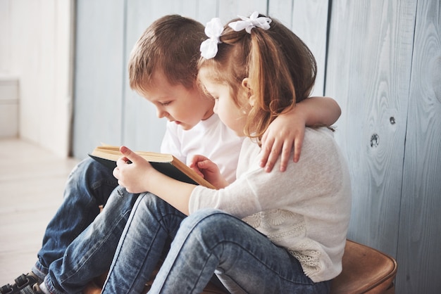 Bereit für große Reisen. Glückliches kleines Mädchen und Junge, die das intereting Buch trägt einen großen Aktenkoffer und ein Lächeln liest. Reisen, Freiheit und Vorstellungskraft