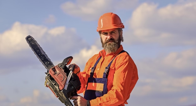 Bereit für Herausforderungen Baumeister Kettensäge Heimwerkerwerkstatt Kreativität und Übung Handwerker Kopfschutz im Helm Verbesserung und Renovierung Brutaler Baumeister Ingenieur Baumeister in Uniform