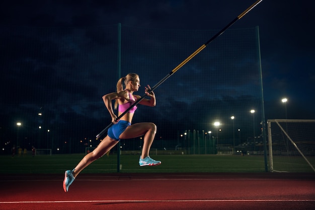 Bereit, Schwierigkeiten zu überwinden. Professionelles Stabhochspringertraining am Abend im Stadion. Üben im Freien. Konzept des Sports