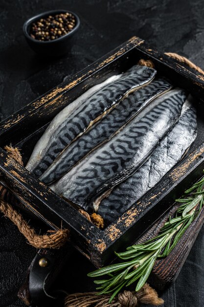 Bereit zum Kochen geschnittener roher Makrelenfiletfisch in einer Holzkiste mit Kräutern Schwarzer Hintergrund Ansicht von oben