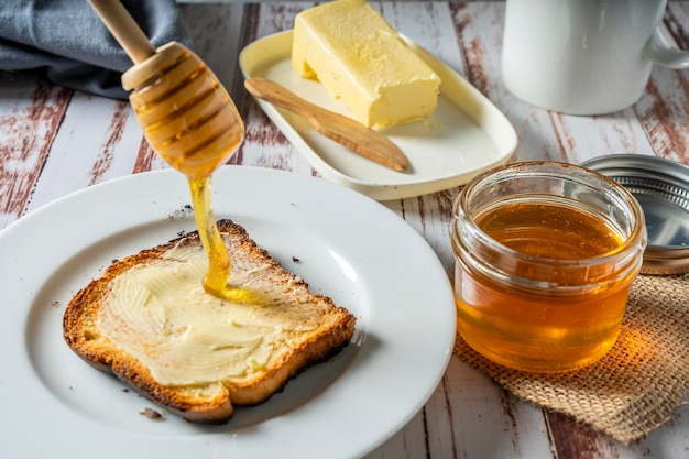 Bereiten Sie ein gesundes Frühstück mit einem Toast mit Butter und reinem Bio-Bienenhonig zu. Gesundes Lebensmittelkonzept.