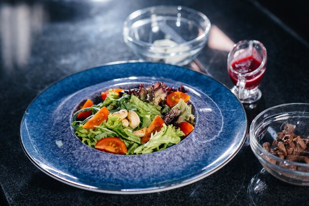 Bereiten Sie einen köstlichen frischen Salat aus Tomatengrün, Käse, Kalbfleisch und Cashewnüssen zu. Leckeres gesundes Essen.