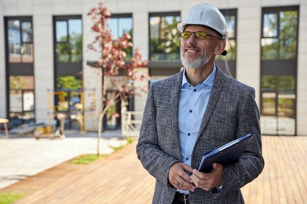 Bereitstellung von städtebaulichem erfolgreichen Architekten-Ingenieur-Manager mittleren Alters mit Helm lächelnd