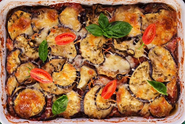 Berenjena al horno con queso en una mesa de madera oscura Parmigiana melanzane Vista superior cocina italiana