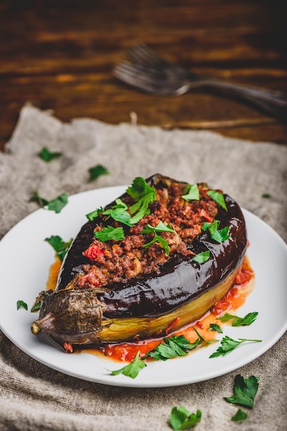 Berenjena al horno rellena con tomates de carne molida y especias en un plato blanco Plato tradicional Karniyarik de la cocina turca