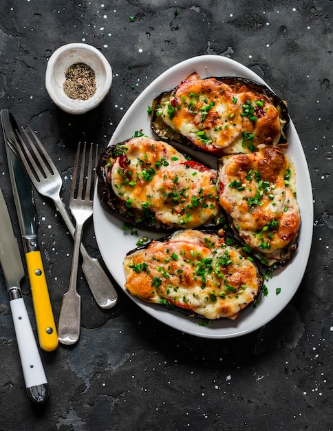 Berenjena al horno con tomates de jamón y mozzarella deliciosas tapas de aperitivo en una vista superior de fondo oscuro