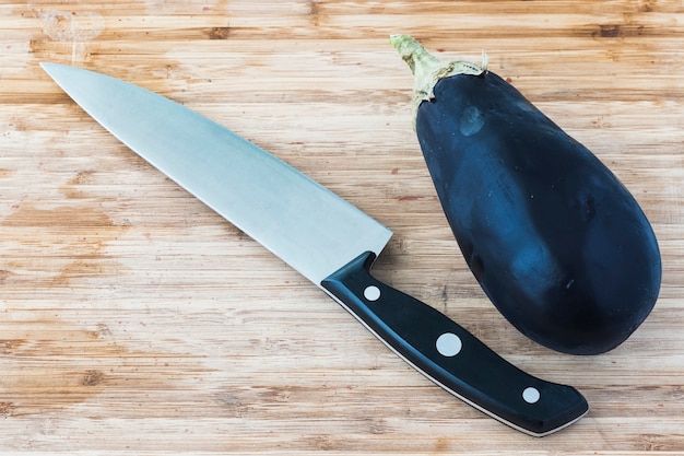 Berenjena en tablero de madera con un cuchillo y copia espacio