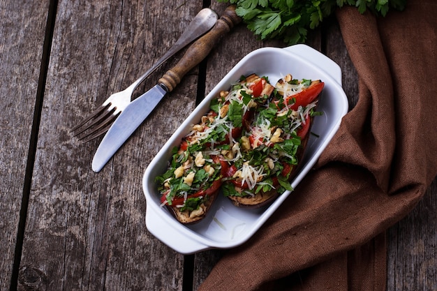 Berenjenas al horno con queso, tomate, hierbas y nuez. Enfoque selectivo