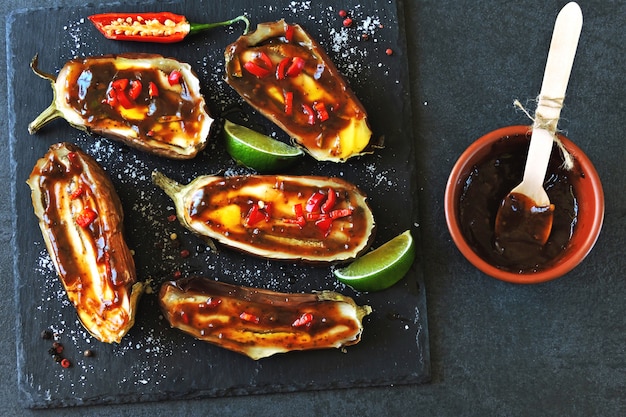 Berenjenas al horno con salsa de chile limón en un tablero de piedra.