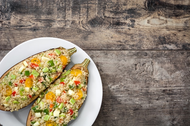 Berenjenas rellenas con quinua y verduras sobre fondo de madera