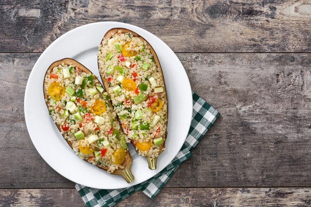 Foto berenjenas rellenas con quinua y verduras sobre fondo de madera