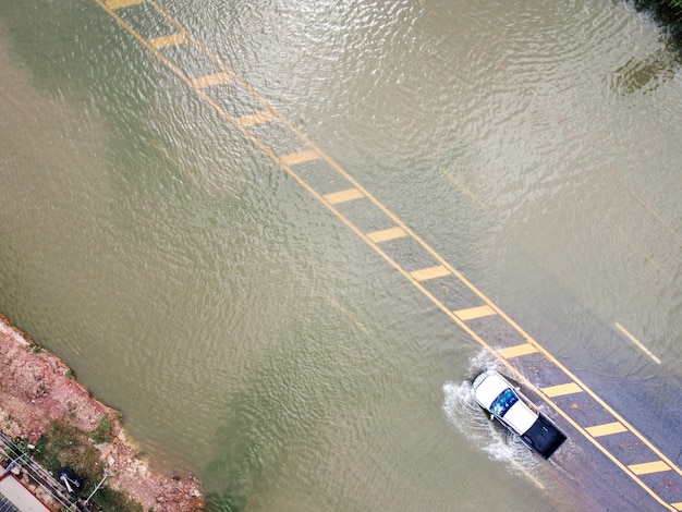Überflutete Straßen, Menschen mit durchfahrenden Autos. Luftaufnahmen mit Drohnen zeigen überflutete Straßen und vorbeifahrende Autos mit Spritzwasser.