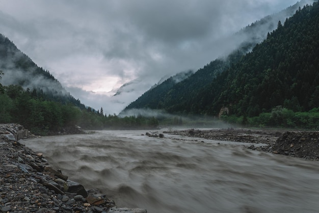 Überfluteter Fluss nach starkem Regen in den nebligen Bergen