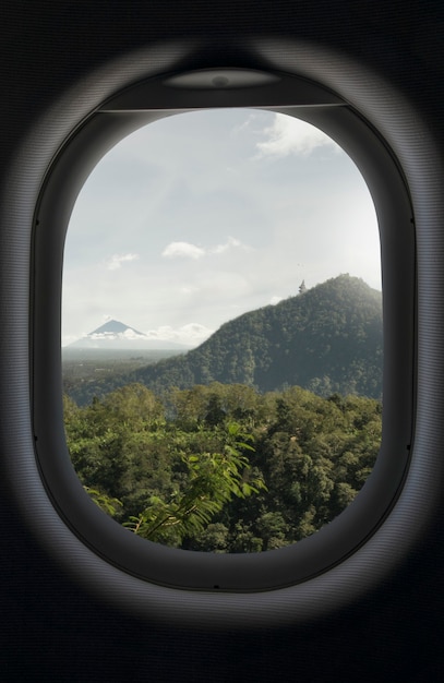 Berg, grüner tropischer Wald und Himmelansicht von einem Flugzeugfenster. Go Reisebuchungskonzept