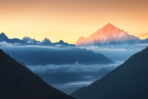 Berge und niedrige Wolken bei buntem Sonnenaufgang in Nepal