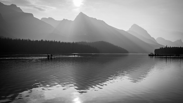 Berge und Sonne spiegeln sich im noch einfarbigen Alpensee Jasper NP Kanada wider