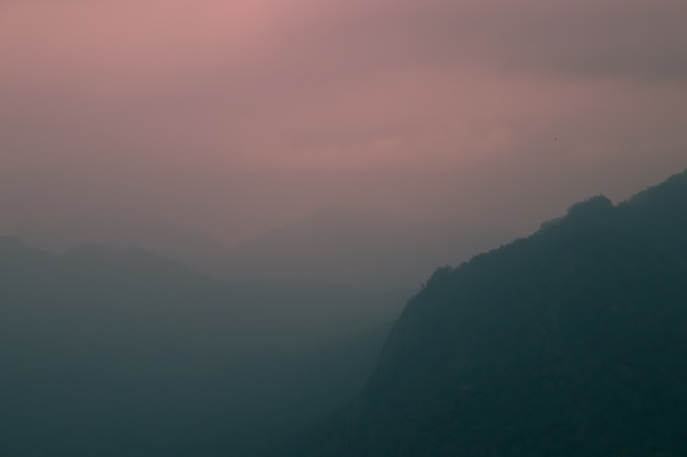 Berge zur Sonnenuntergangzeit bedeckt im Nebel