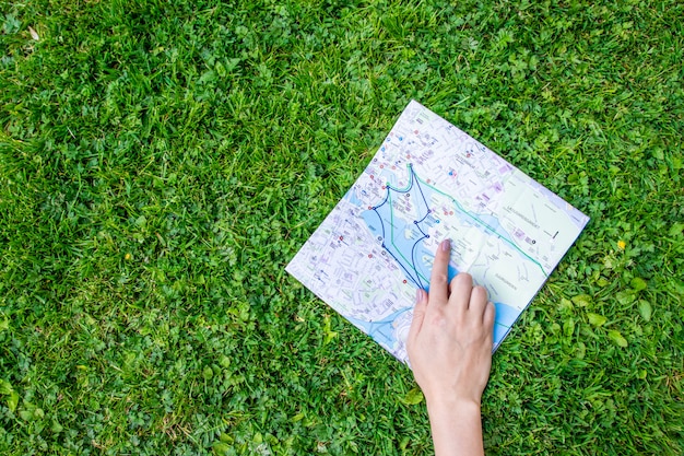 Übergeben Sie das Halten eines Papierblattes mit der Reisekarte über grünem Waldnaturhintergrund.