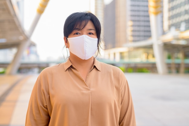 Übergewichtige asiatische Frau mit Maske an der Skywalk-Brücke