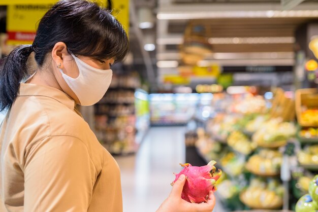 Übergewichtige asiatische Frau mit Maske zum Schutz vor dem Ausbruch des Koronavirus im Supermarkt