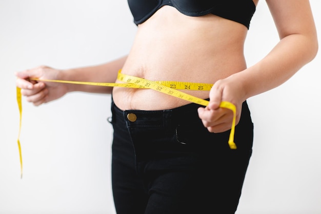 Übergewichtige Frau, die ihren fetten Bauch mit einem Maßband misst Übergewichtiger fetter Bauch der Frau fette Frau fettes Mädchen Frauendiät-Lifestyle-Konzept zur Reduzierung des Bauches