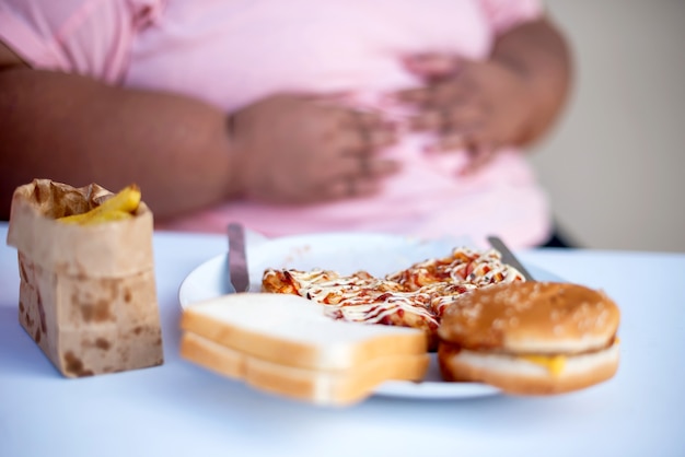 Übergewichtige Frau, die ungesunde Fertigkost isst