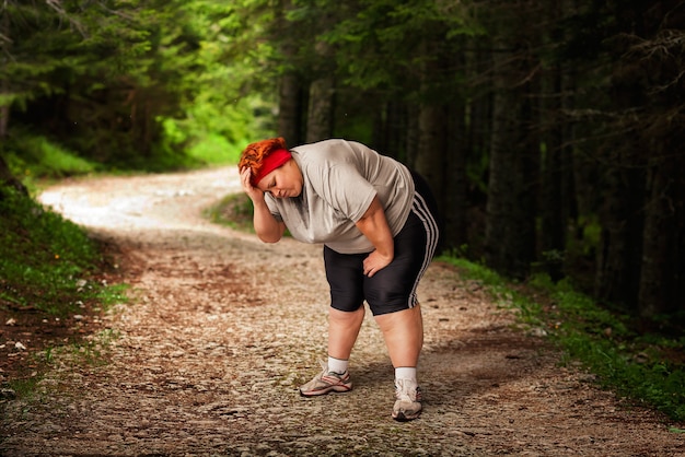 Übergewichtige Frau müde nach einem Lauf im Wald.