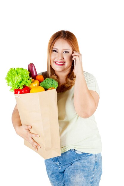 Übergewichtige Frau trägt Papiertüte mit Gemüse