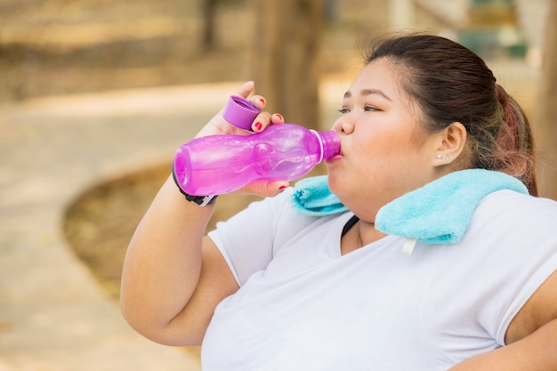 Übergewichtige Frau trinkt Wasser nach dem Training