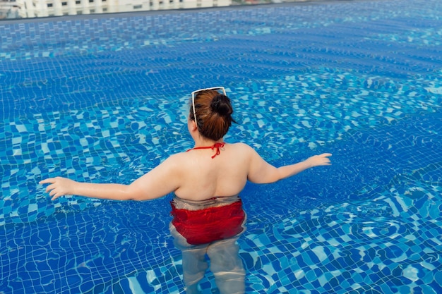 Übergewichtige junge asiatische Frau im Badeanzug entspannt sich im Pool. Glückliche Plus-Size-Frau, fröhlich, lustig, Urlaubsreisen im Sommer